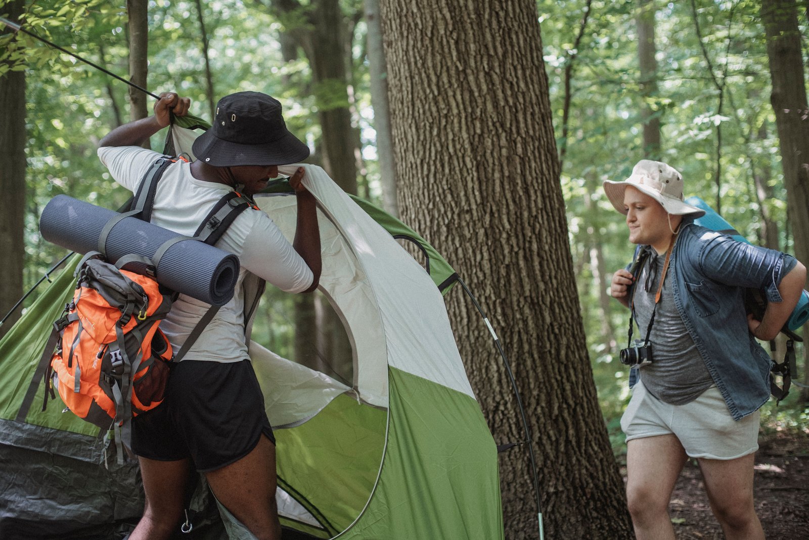 Two people setting up a tent in the woods